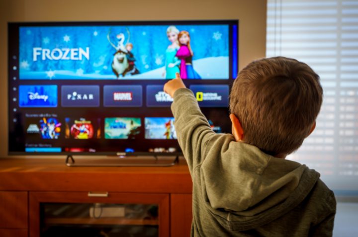 Barcelona, Spain. May 2019 Back view image of cute little boy watching the new Disney plus streaming service and pointing at the TV screen. Illustrative editorial